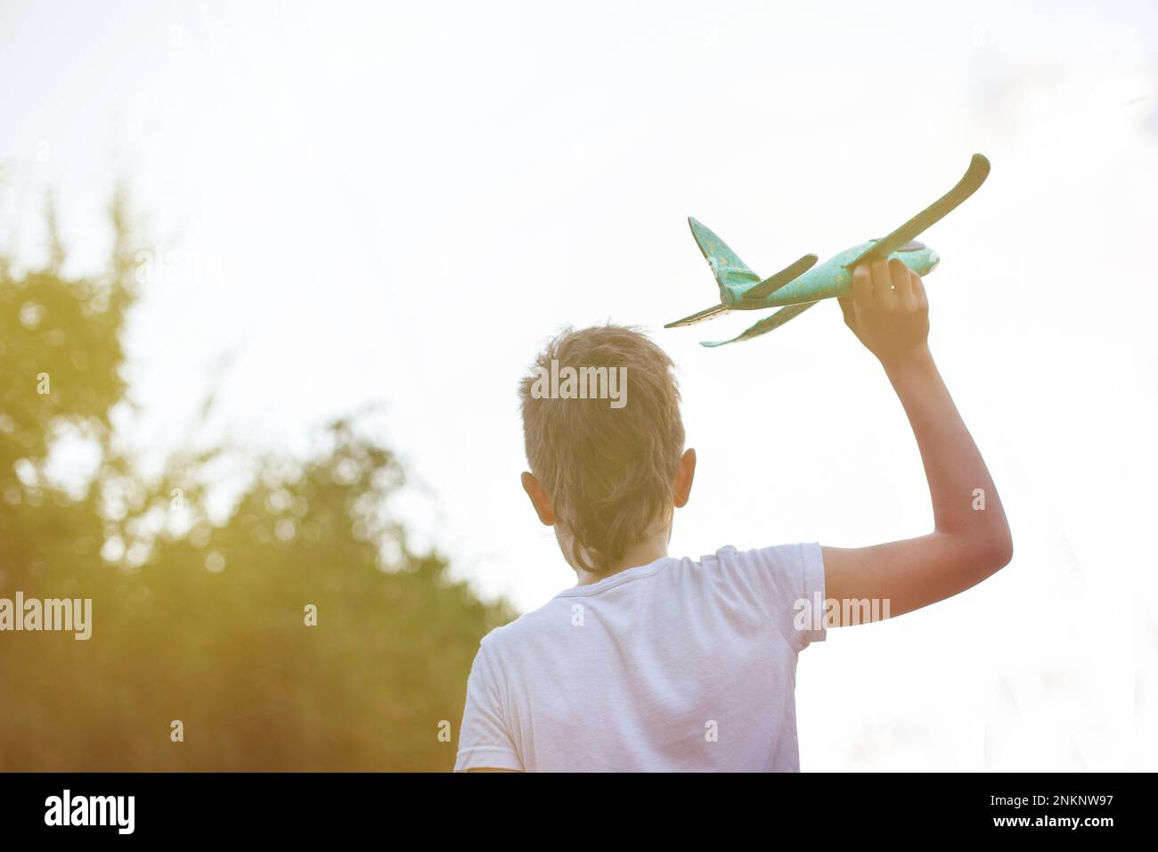 Enfant garçon heureux jouant avec l'avion jouet à l'extérieur. Banque D'Images