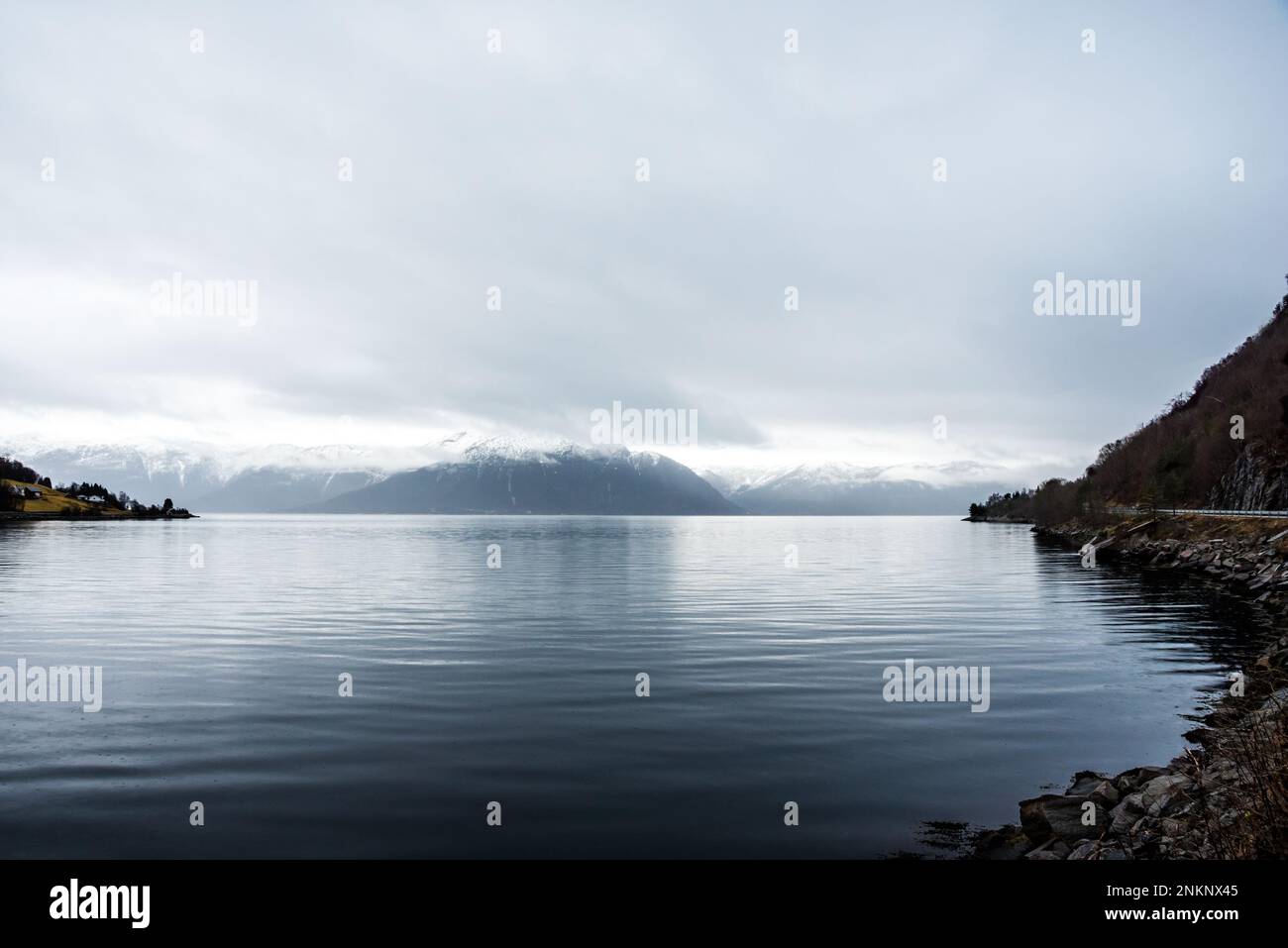 Vue sur un fjord calme avec des montagnes en arrière-plan, avec ciel couvert Banque D'Images
