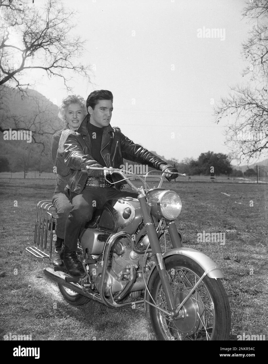 Barbara Stanwyck et Elvis Presley pilotant une moto au set de Roustabout, 1964 Banque D'Images