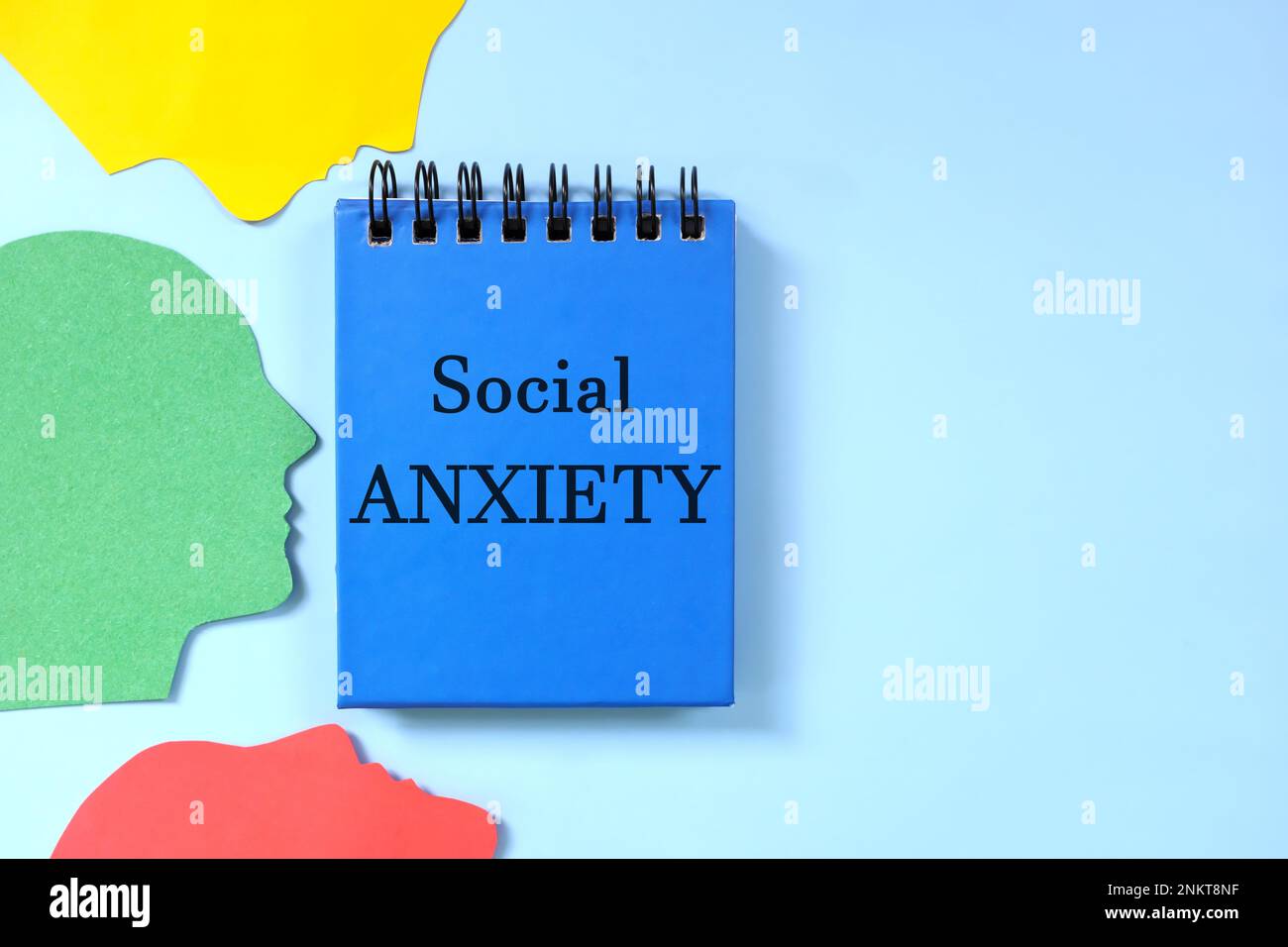 Concept de trouble d'anxiété sociale. Composition de pose plate de profil de tête humaine avec bloc-notes bleu. Banque D'Images