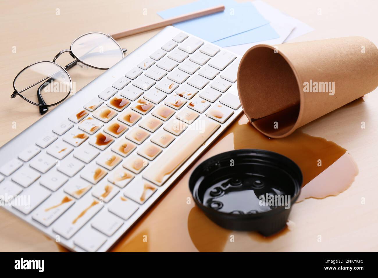 Tasse de café renversée sur le clavier de l'ordinateur sur le bureau en bois Banque D'Images Tasse de café renversée sur le clavier de l'ordinateur sur le bureau en bois Banque D'Images
