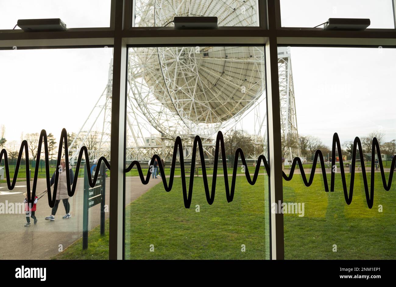 Le radiotélescope géant Lovell sur le site de Jodrell Bank, Cheshire, Royaume-Uni. Vue depuis la fenêtre du centre d'accueil qui est illustrée par des graphiques d'ondes radio. Le cadre qui soutient la parabole est clairement visible de l'arrière / de l'arrière / du côté. (133) Banque D'Images