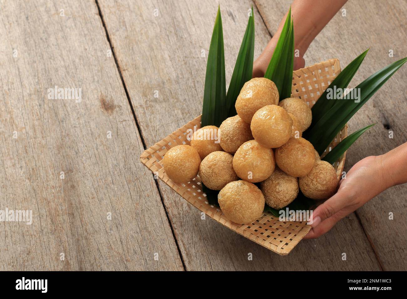 Servi à la main par une femme, Tahu Bulat, tofu de forme ronde, frais de la poêle. Sur une table en bois Banque D'Images