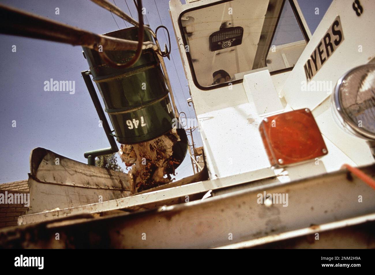 1970s Amérique : les fûts de déchets sont vidés mécaniquement dans la poubelle des camions, faisant partie d'une nouvelle méthode de collecte des déchets parrainée par l'EPA CA. 1972 Banque D'Images
