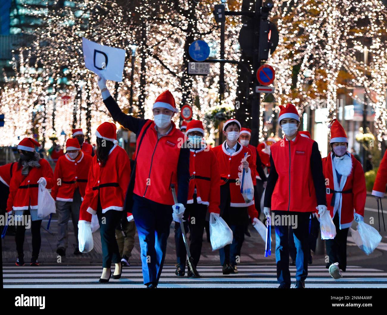 People clad in Santa Clause costume collect garbage near Tokyo Station during an event "Christmas Santa Clean Up Walk 2021" in Tokyo on December 23, 2021. Approximately 200 participants wearing face masks clean the road amid continuing worries over the new coronavirus COVID-19 omicron variant. ( The Yomiuri Shimbun via AP Images ) Banque D'Images