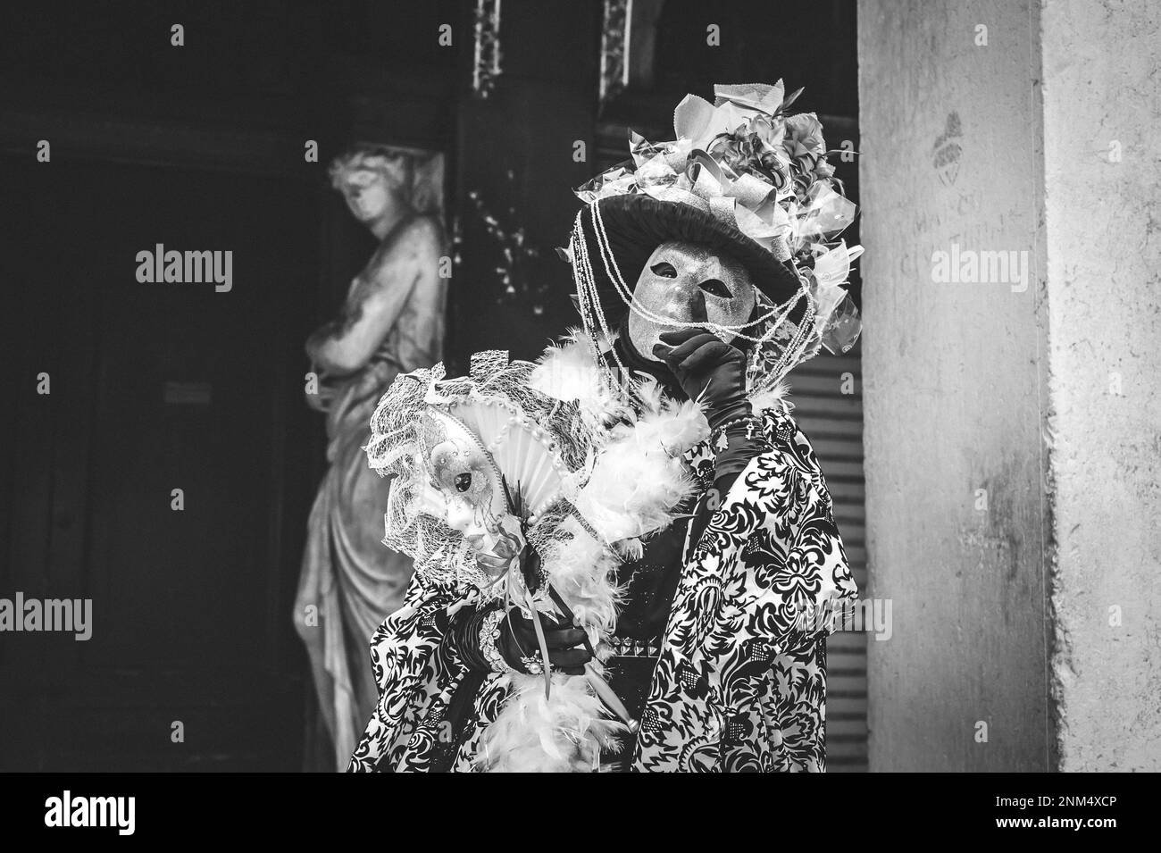 Portrait noir et blanc d'une femme masquée de carnaval à Venise sous une arche Banque D'Images