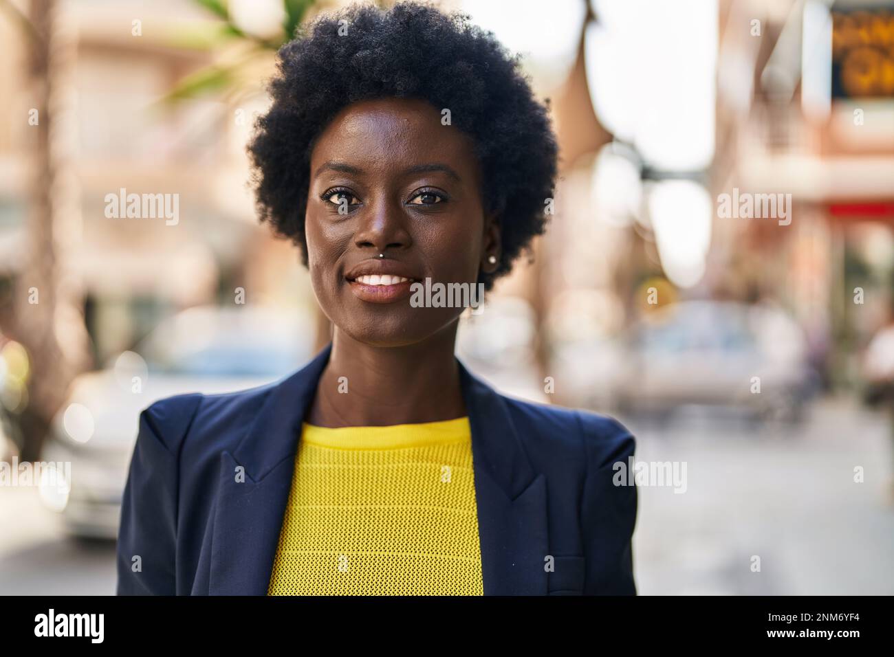Jeune femme afro-américaine d'affaires souriante confiante dans la rue Banque D'Images