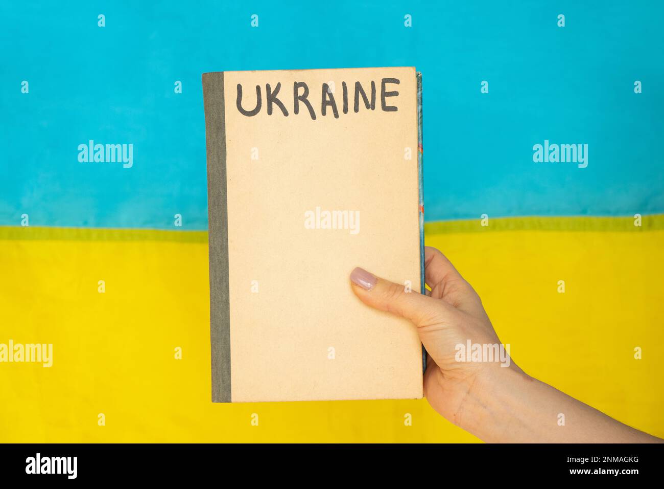 La main d'une femme tient un livre sur lequel l'Ukraine est écrite sur le fond du drapeau de l'Ukraine, l'éducation en Ukraine pendant Banque D'Images