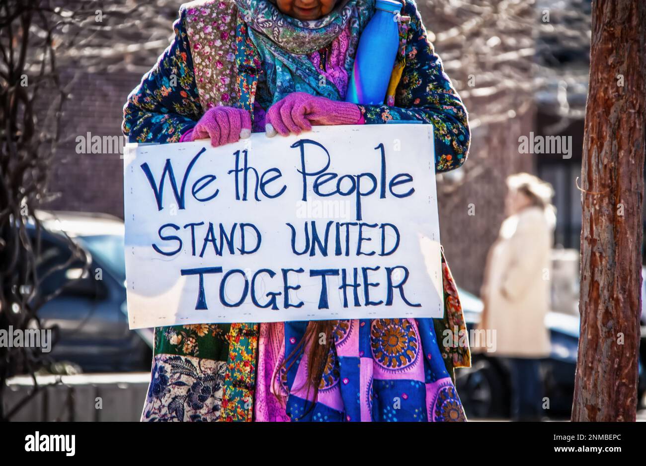 Femme plus âgée en patchwork boho coloré tient signe de protestation lisant nous, les gens se tiennent Unis ensemble - arrière-plan flou Banque D'Images