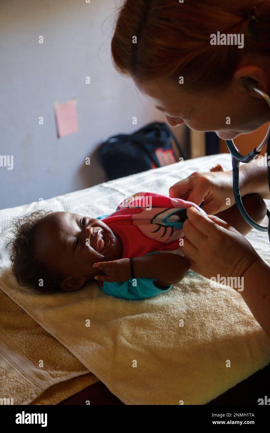 Un médecin blanc examinant un bébé noir avec un stéthoscope. Banque D'Images