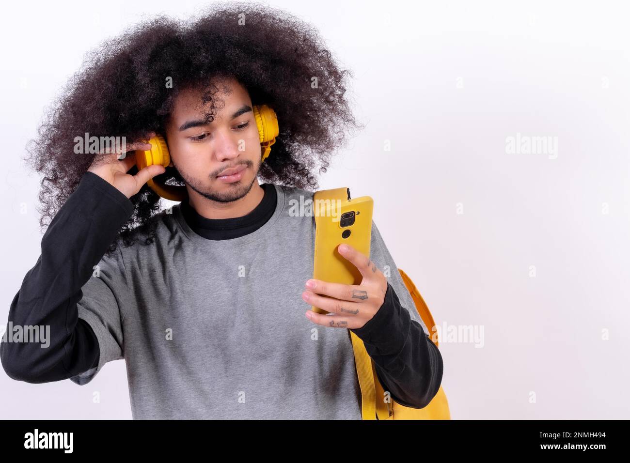 Jeune homme aux cheveux afro sur fond blanc, écoutant de la musique en streaming en ligne Banque D'Images