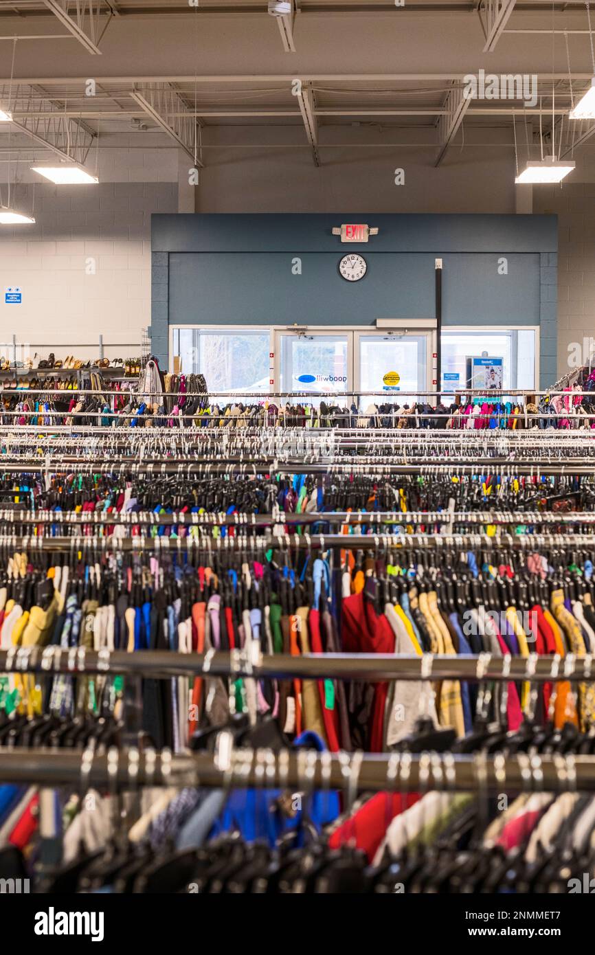 Plusieurs porte-vêtements, premier plan, dans un magasin thrift (bonne volonté) regardant vers la porte d'entrée, arrière-plan, à Ludington, Michigan, États-Unis. Banque D'Images