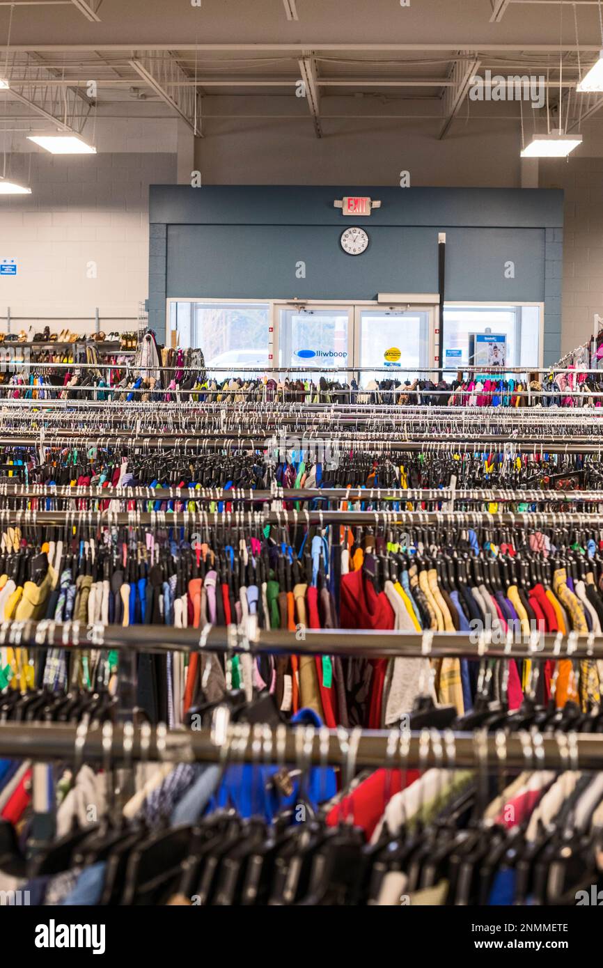 Plusieurs porte-vêtements, premier plan, dans un magasin thrift (bonne volonté) regardant vers la porte d'entrée, arrière-plan, à Ludington, Michigan, États-Unis. Banque D'Images