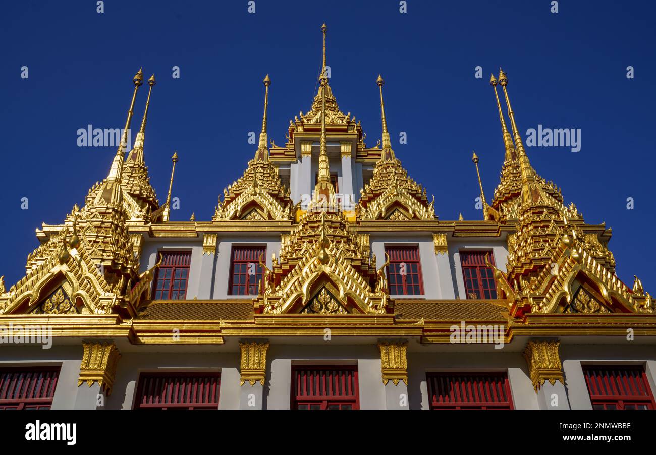 Détail des flèches dorées contre le ciel bleu de Loha Prasat, château de fer officiellement appelé Wat Ratchanatdaram Worawihan à Bangkok. Banque D'Images