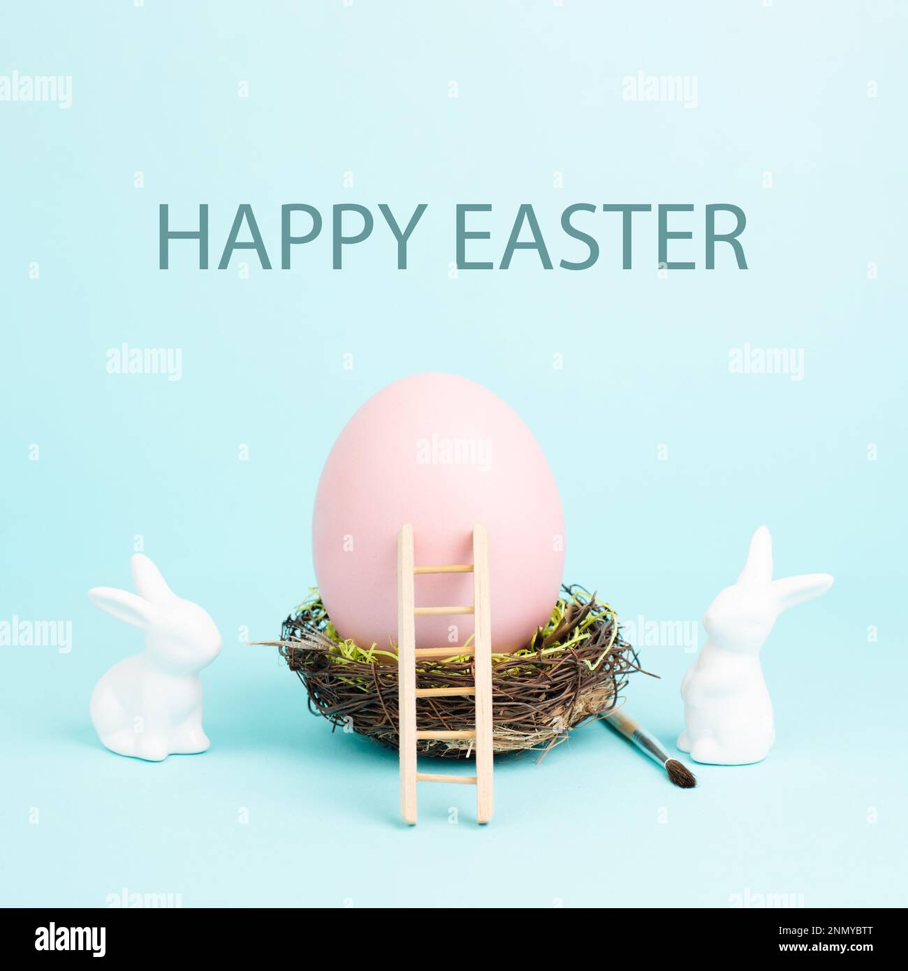 Lapin ou lapin de Pâques assis à côté d'un énorme œuf de couleur rose dans un nid d'oiseaux, pinceau et échelle, vacances de printemps Banque D'Images