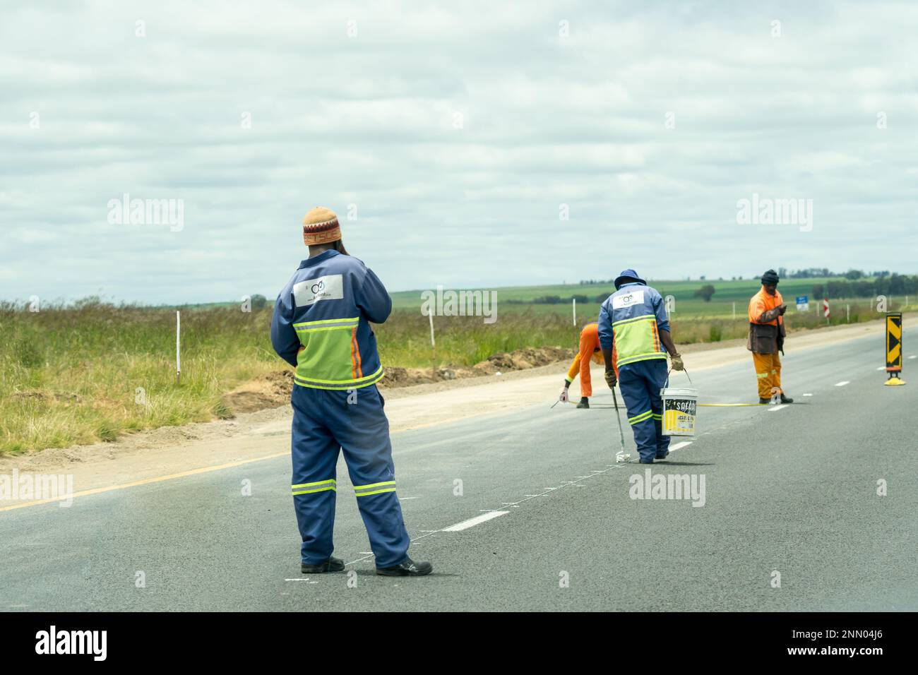 Travailleurs de la route sud-africains employés pour peindre des lignes sur une autoroute habillée de combinaisons ou d'uniformes travaillant dans l'État libre, Afrique du Sud sur l'entretien de la route Banque D'Images