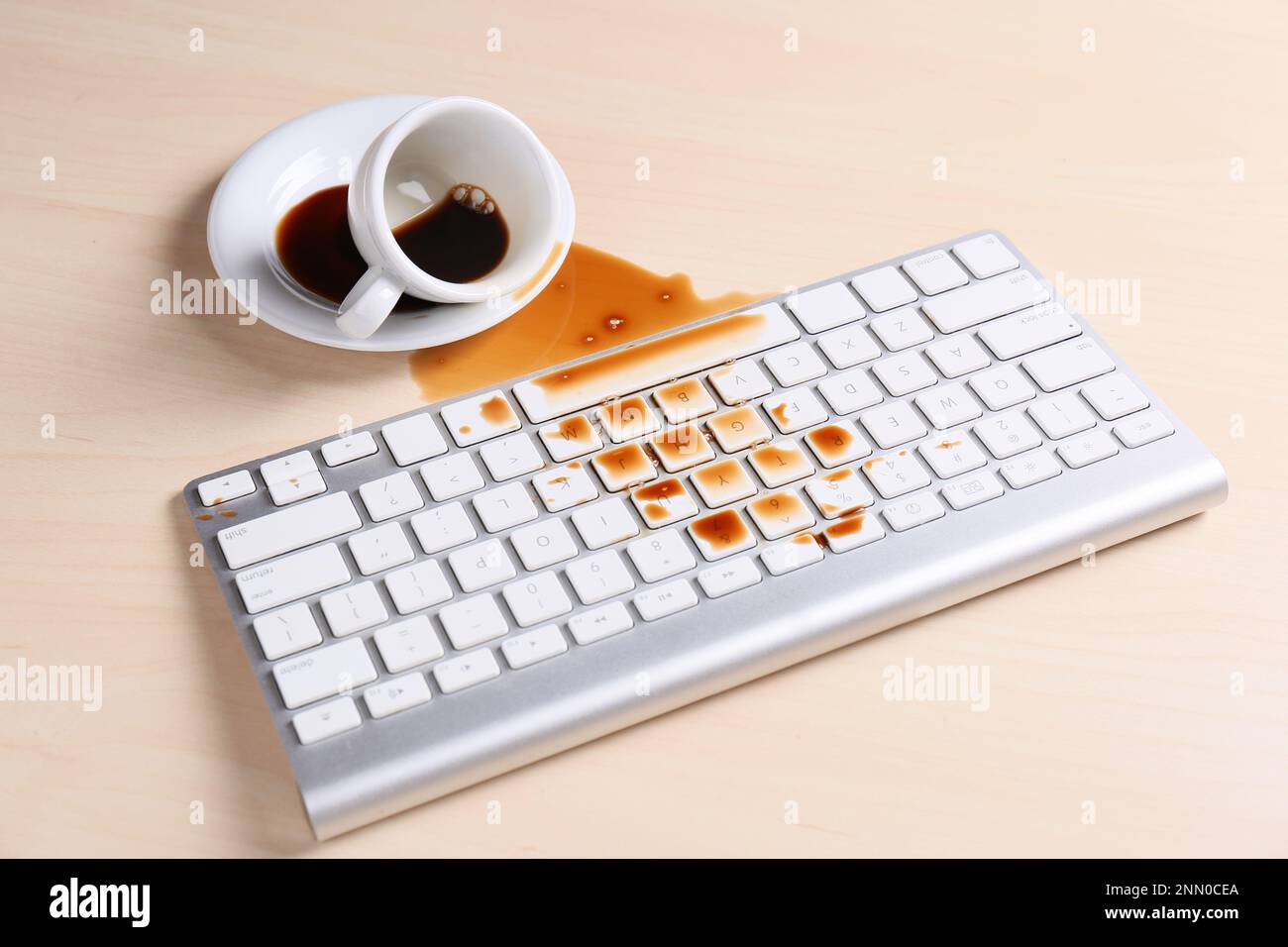 Tasse de café renversée sur le clavier de l'ordinateur sur une table en bois Banque D'Images Tasse de café renversée sur le clavier de l'ordinateur sur une table en bois Banque D'Images