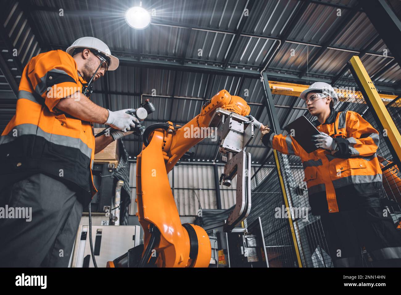 L'équipe d'ingénieurs assure le service de soudage des robots travaillant dans l'usine d'automatisation. Les personnes travaillant en costume de sécurité travaillent robotique ARM logiciel de programmation ou de remplacement par Banque D'Images