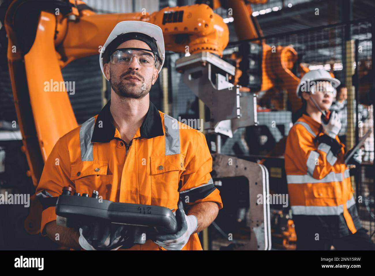 L'équipe d'ingénieurs assure le service de soudage des robots travaillant dans l'usine d'automatisation. Les personnes travaillant en costume de sécurité travaillent robotique ARM logiciel de programmation ou de remplacement par Banque D'Images