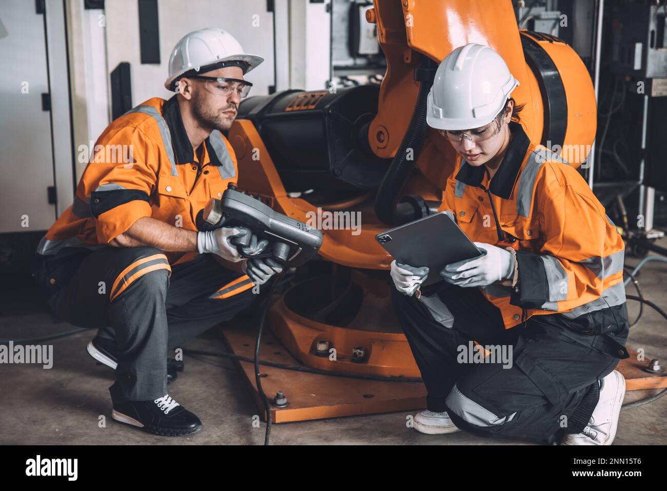 L'équipe d'ingénieurs assure le service de soudage des robots travaillant dans l'usine d'automatisation. Les personnes travaillant en costume de sécurité travaillent robotique ARM logiciel de programmation ou de remplacement par Banque D'Images