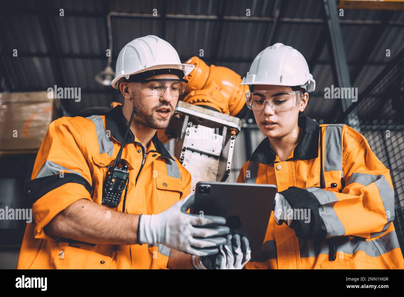 L'équipe d'ingénieurs assure le service de soudage des robots travaillant dans l'usine d'automatisation. Les personnes travaillant en costume de sécurité travaillent robotique ARM logiciel de programmation ou de remplacement par Banque D'Images