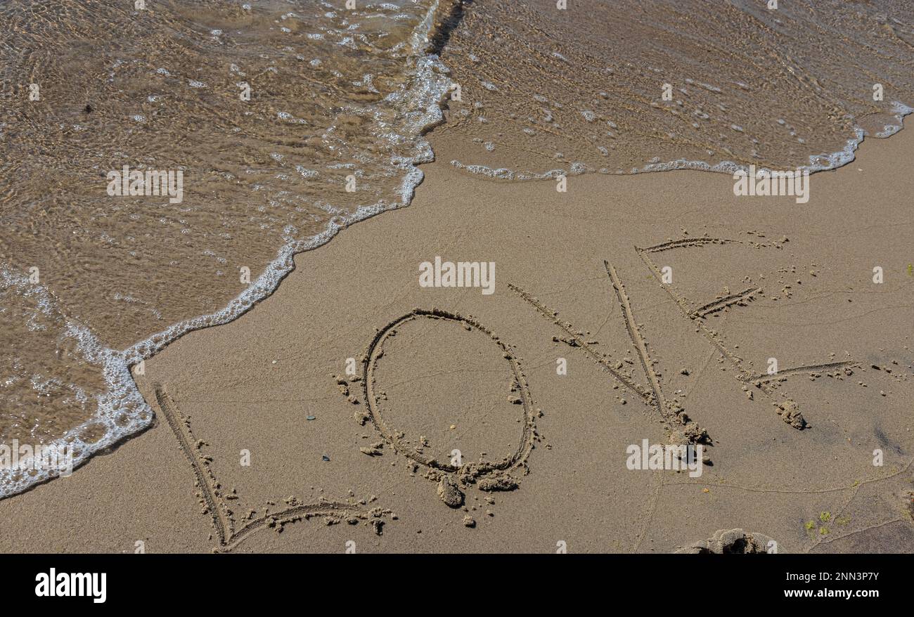 Inscription Love dessiné sur le sable. Concept de sentiments romantiques vrais et honnêtes. spa roman sur la mer. Banque D'Images