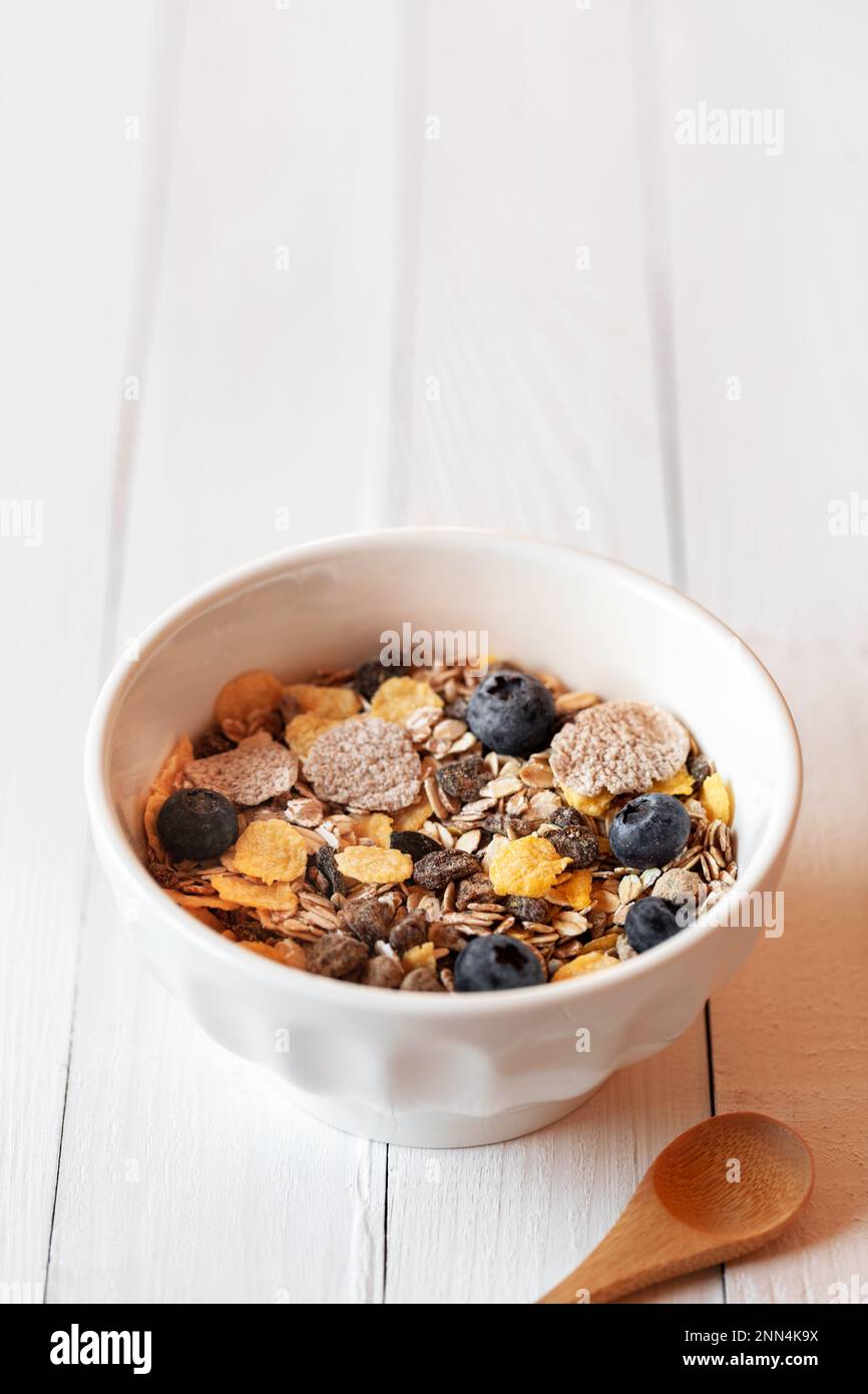 bol petit déjeuner d'avoine, de maïs et de flocons orthographiés et de baies fraîches sur la table en bois blanc, espace copie Banque D'Images