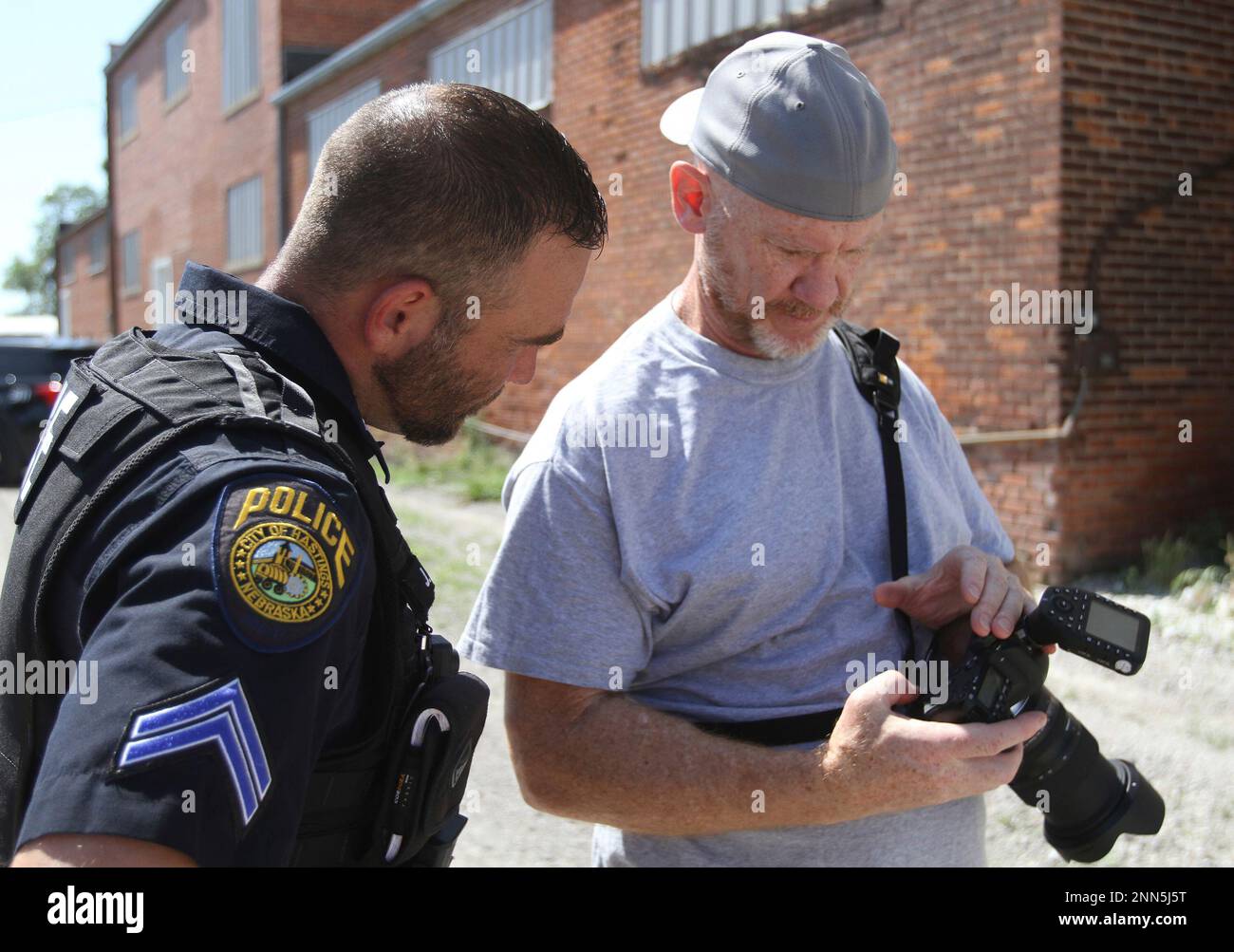 Charlie SImmons, right, founder of Badges Across America, shows photos to Corporal John Adams, of the Hastings Police Department Wednesday, June 16, 2021 in Hastings, Neb. As a deputy-turned-photographer, Charlie Simmons of Aurora, Colorado, wants to take pictures that highlight the pride and dedication law enforcement officers have in their jobs. That’s the goal of the nonprofit organization he founded in 2018, Badges Across America. (Amy Roh/The Hastings Tribune via AP) Banque D'Images