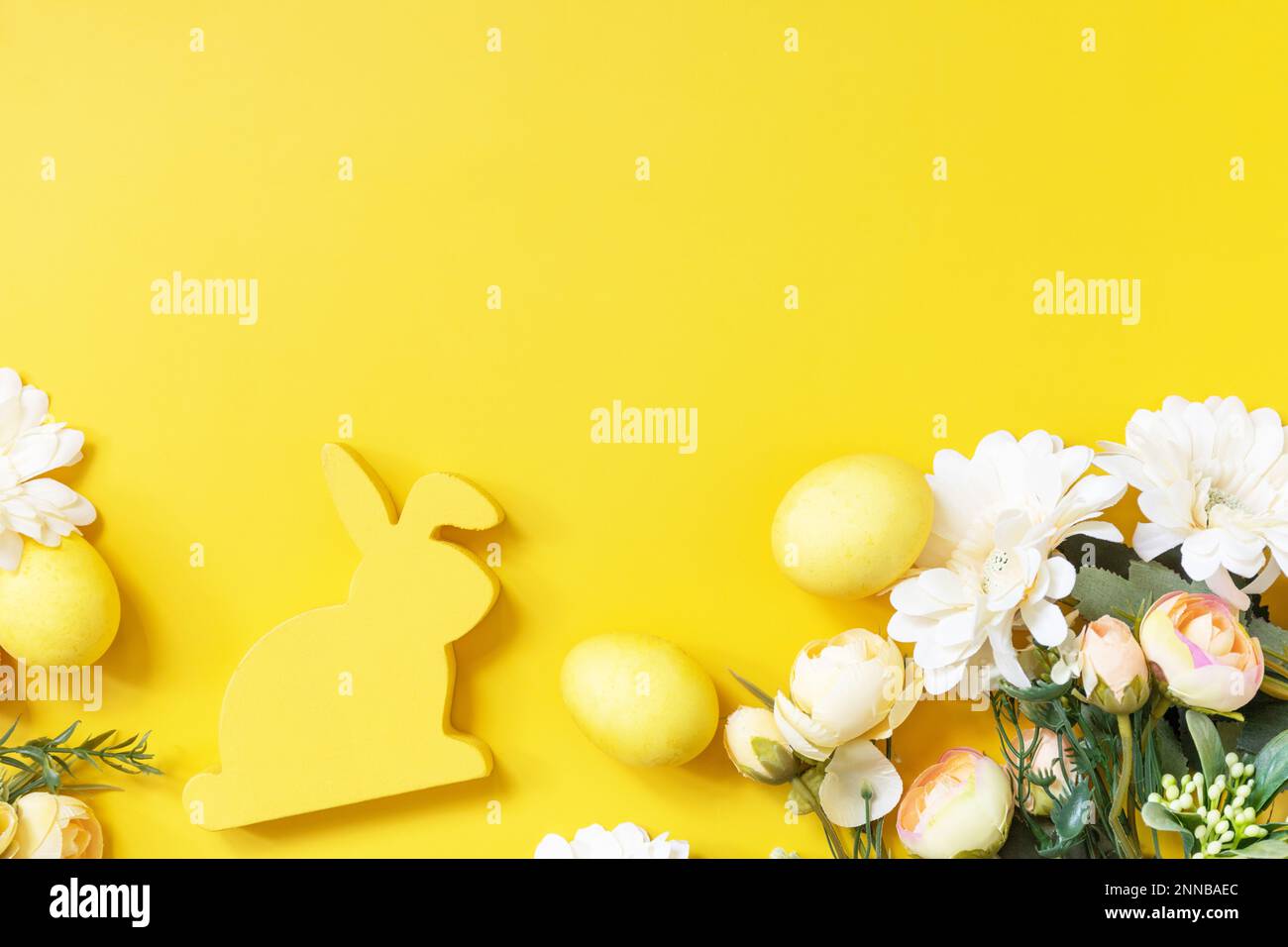 Composition de Pâques avec œufs colorés, lapin en bois et fleurs de printemps sur fond jaune. Vue de dessus. Copier l'espace. Banque D'Images