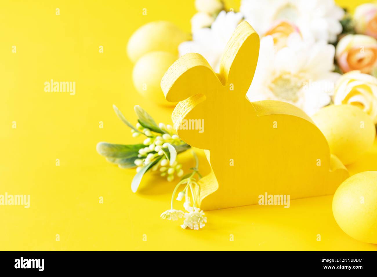 Composition de Pâques avec œufs colorés, lapin en bois et fleurs de printemps sur fond jaune. Copier l'espace. Banque D'Images