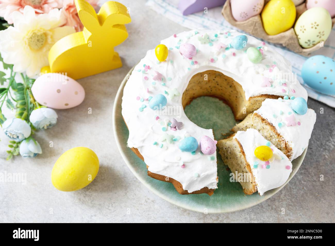 Joyeuses Pâques, délicieux dessert. Gâteau de pâques glacé au citron décoré de confiseries et de mini-bonbons aux œufs de chocolat sur fond de pierre grise. Banque D'Images