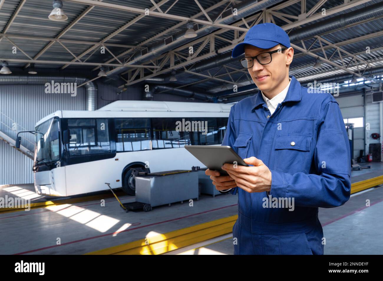 Chef de service avec tablette numérique sur l'arrière-plan du bus dans le garage Banque D'Images