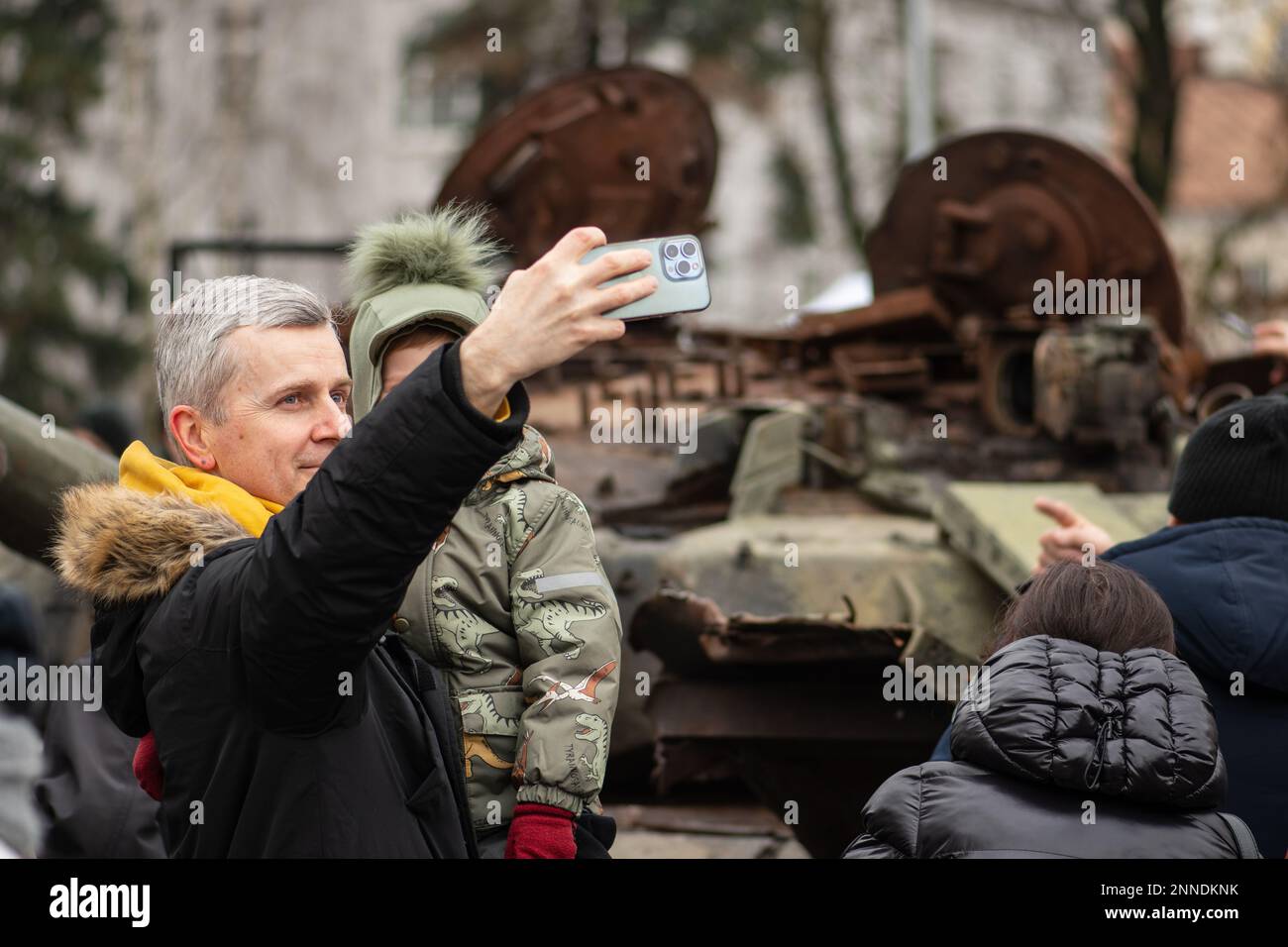 Père et fils emportant un selfie près d'un épave rouillée et fondue d'un char russe soviétique T-72B détruit lors de l'invasion russe de l'Ukraine Banque D'Images