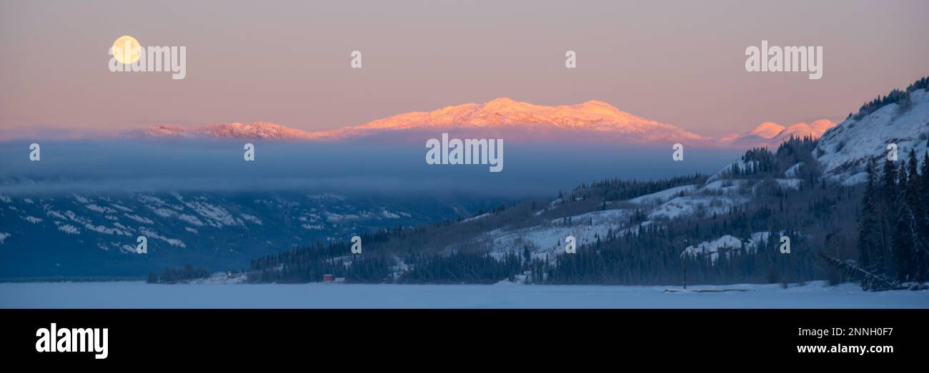 Lever de soleil sur un grand lac gelé avec cadre de lune et ciel rose pastel et tons dans le ciel. Banque D'Images