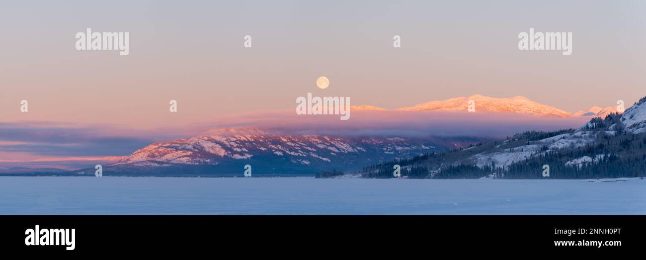Lever de soleil sur un grand lac gelé avec cadre de lune et ciel rose pastel et tons dans le ciel. Banque D'Images