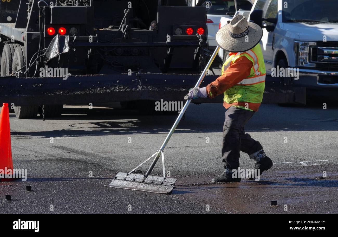 Le travailleur routier portant des vêtements et des bottes de protection lisse le joint de lisier frais Banque D'Images