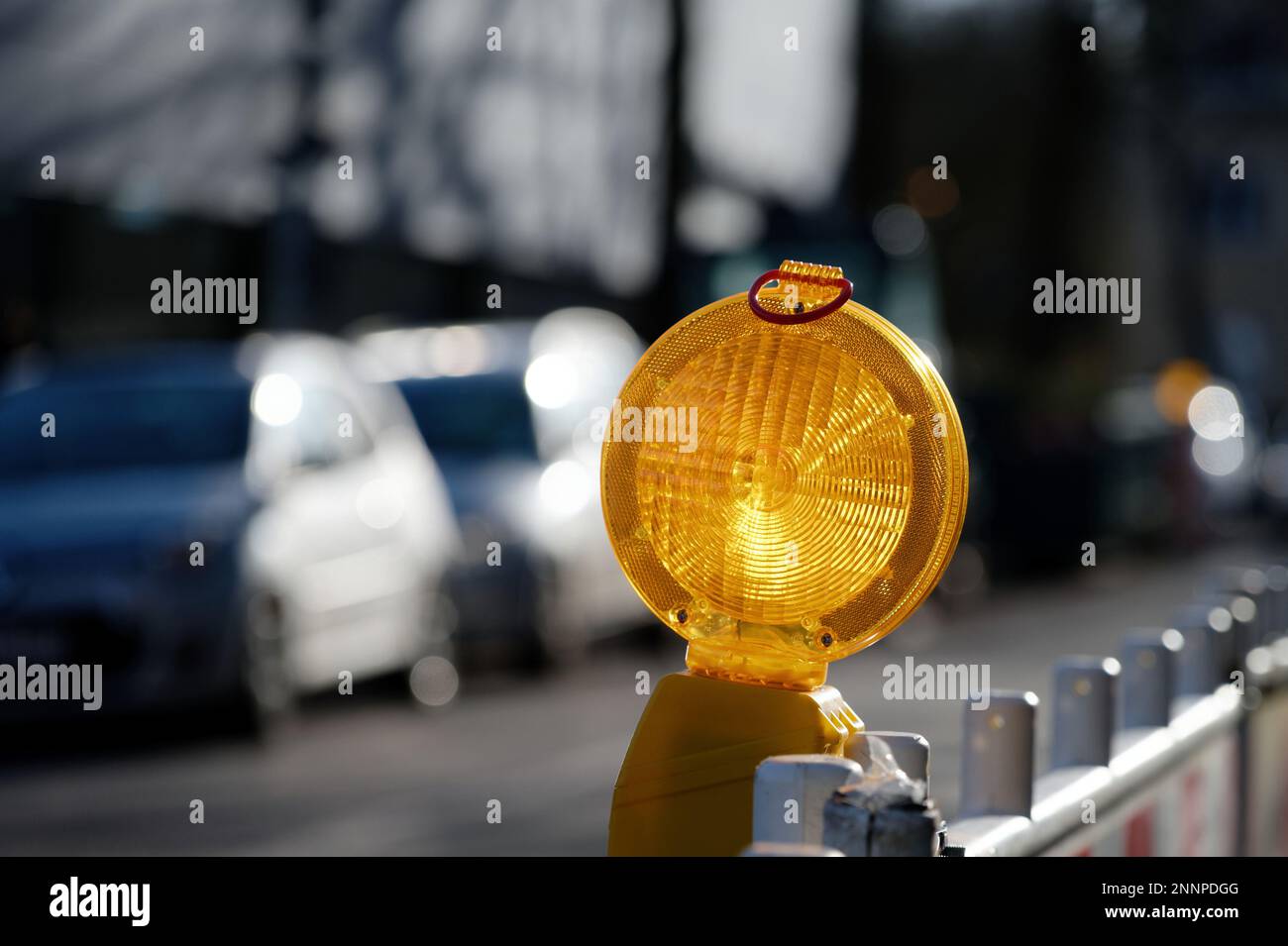 lumière du chantier de construction éclairée sur une grille de barrière d'un chantier de construction de route devant un arrière-plan flou Banque D'Images