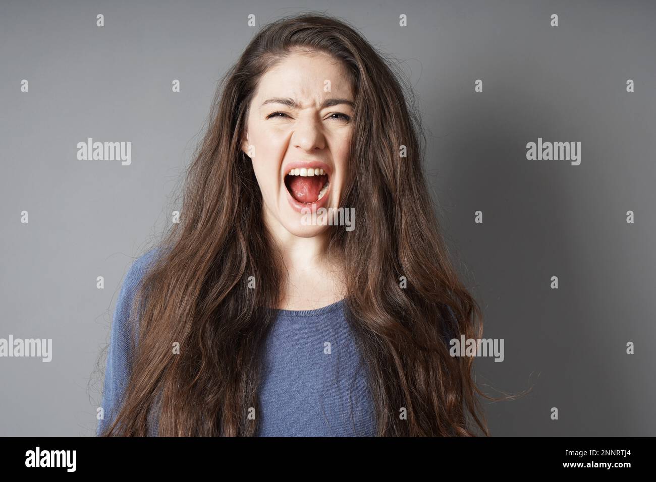 Jeune femme hystérique en colère crier et crier - fond gris with copy space Banque D'Images