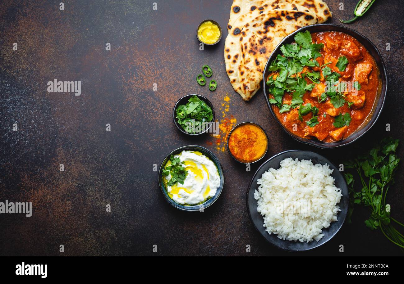 Plat indien traditionnel poulet tikka masala avec espace pour le texte. Viande de curry épicée dans un bol, riz basmati, pain naan, sauce raita au yaourt sur rustique Banque D'Images