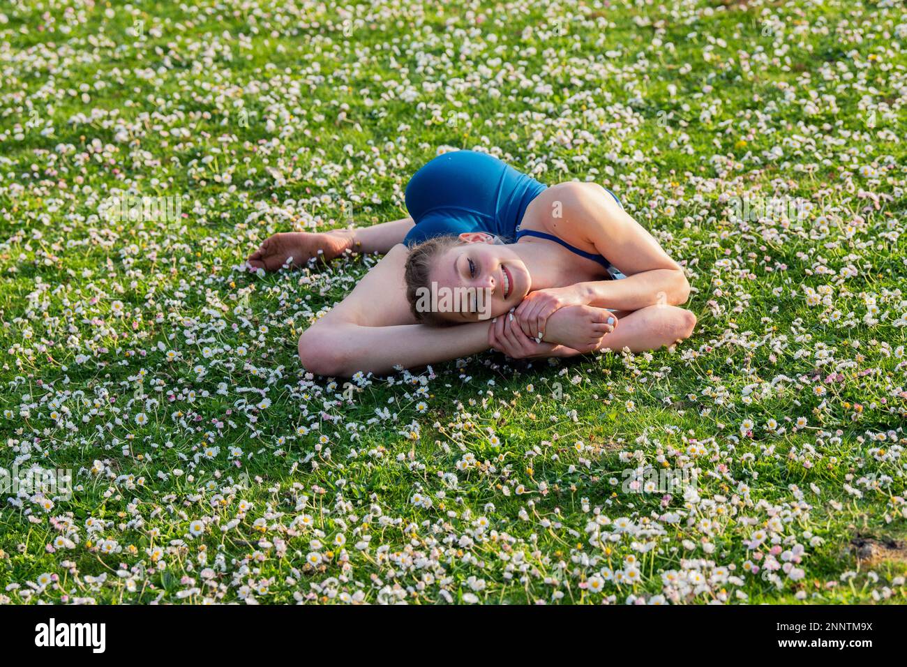 Contorsionniste couché sur une pelouse avec des pâquerettes, parc de Battle point, île de Bainbridge, Washington, États-Unis Banque D'Images
