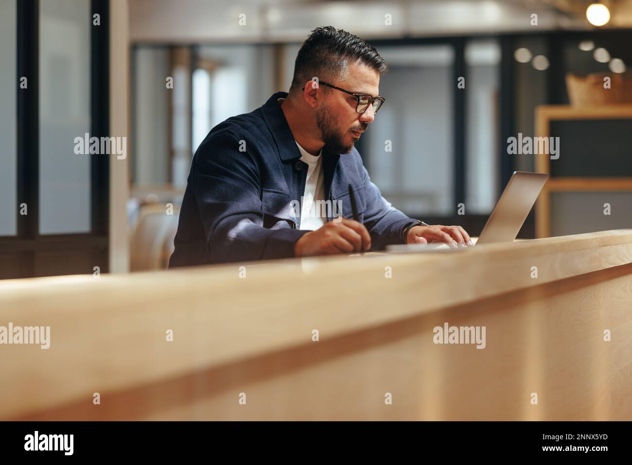 Graphiste travaillant sur un ordinateur portable dans un bureau de collègue. Homme d'affaires créatif qui dessine un nouveau design sur une tablette graphique. Concevoir un travail professionnel Banque D'Images