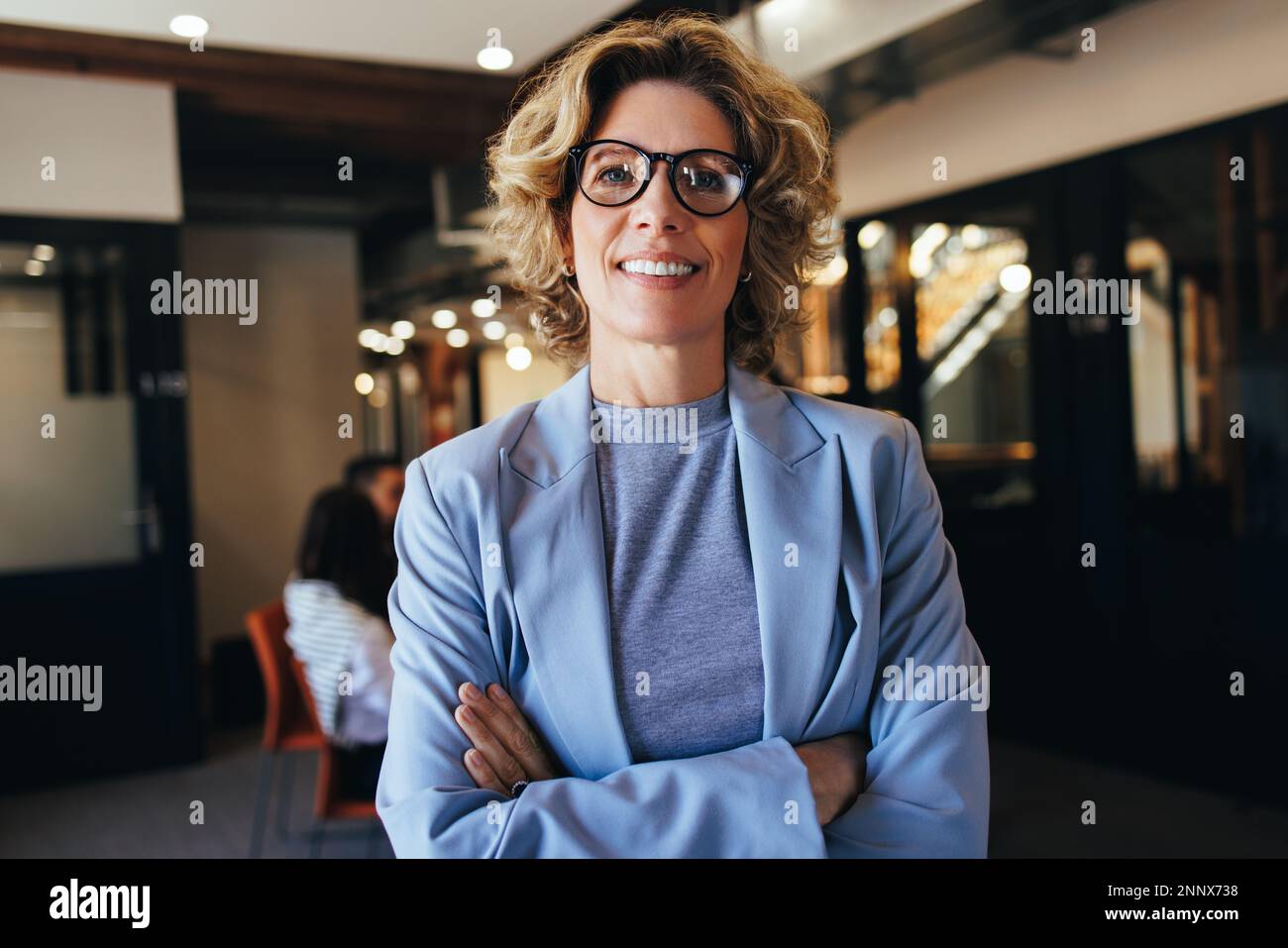 Portrait d'une femme d'affaires debout dans un bureau avec des bras croisés. Femme professionnelle vêtue d'un costume. Femme travaillant dans un lieu de travail d'entreprise, elle Banque D'Images