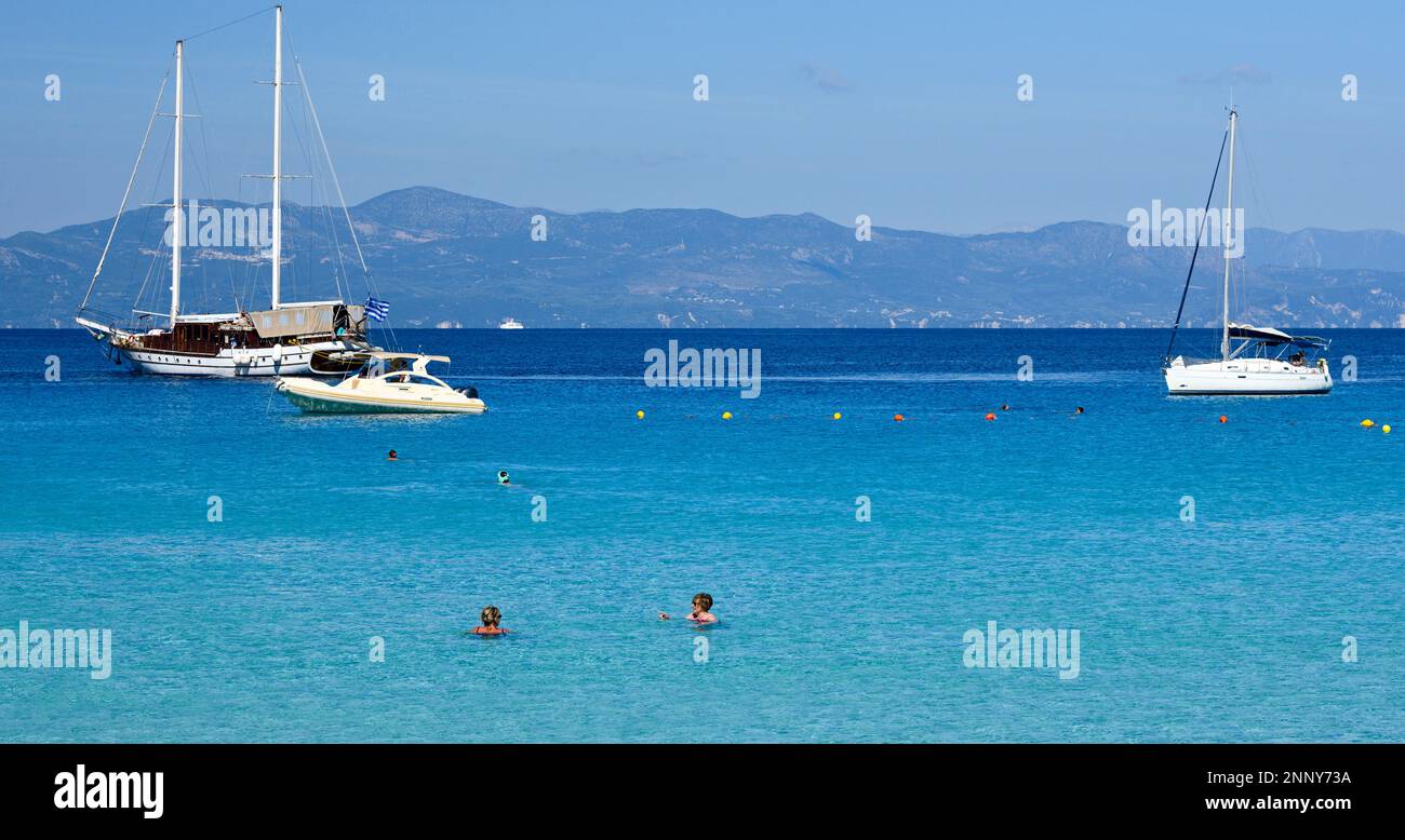 Touristes sur la plage et voiliers dans la baie de Lakka, Paxos, Iles Ioniennes, Grèce Banque D'Images