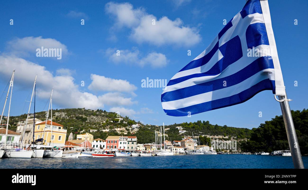 Drapeau grec et bateaux dans les docks, Gaios, Paxos, Iles Ioniennes, Grèce Banque D'Images