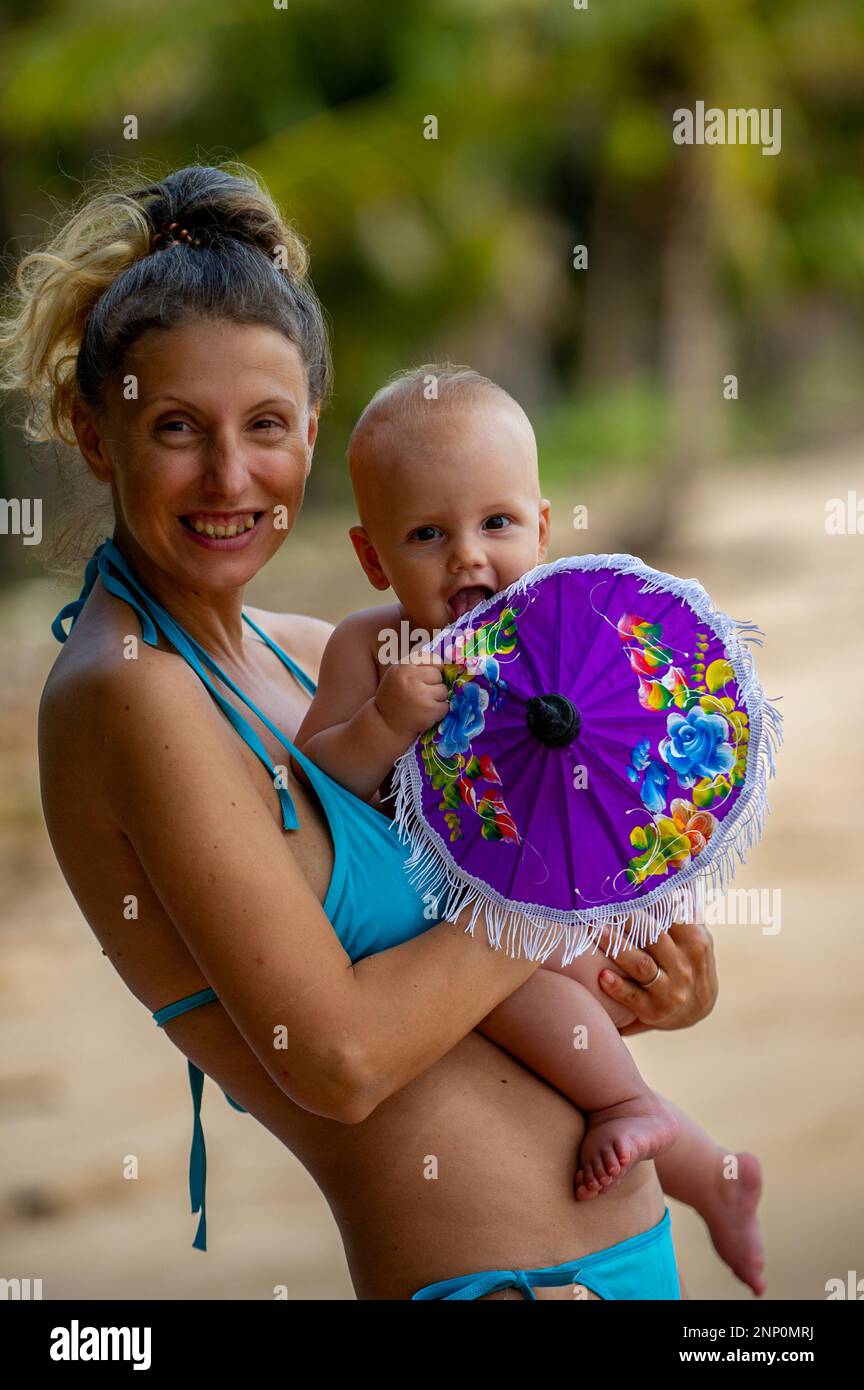 Bébé nouveau-né rit dans les bras de mère sur la plage jouant avec un petit parapluie  violet Photo Stock - Alamy