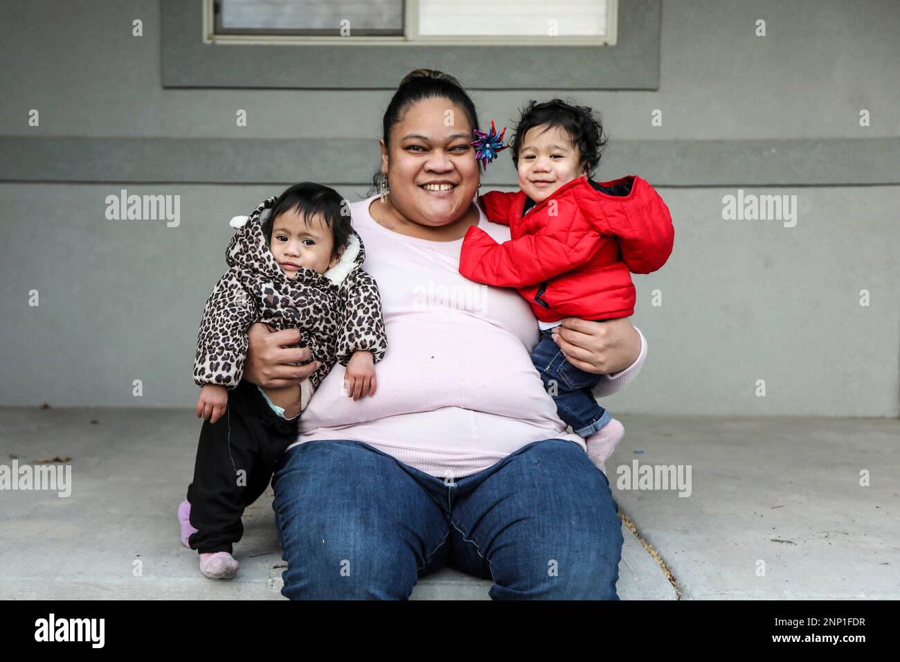 Lorimay Fuimaono-Ki poses for a portrait outside of a relative's home with her twins, Lyrica-Teuila, left, and Lima, right, in Provo, Utah, on Jan. 8, 2021. The young mother cannot stop the tears as she tries to explain what life has been like since her home, the U.S. territory of American Samoa, closed its borders to keep COVID-19 from ravaging the tiny string of Pacific Islands and atolls. (Annie Barker/The Deseret News via AP) Banque D'Images