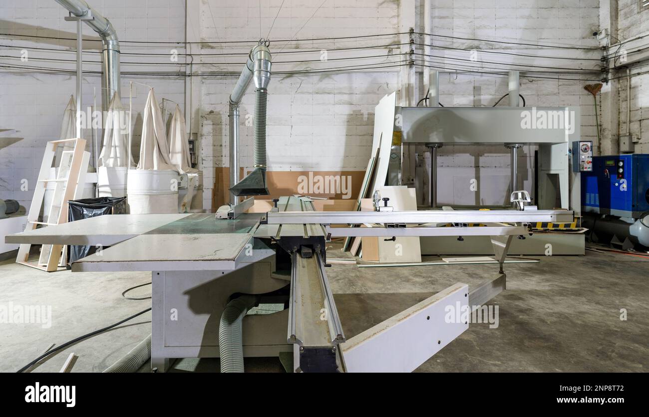 Grande scie à table coulissante avec pare-poussière en usine industrielle produisant des pièces de meubles en bois. Banque D'Images