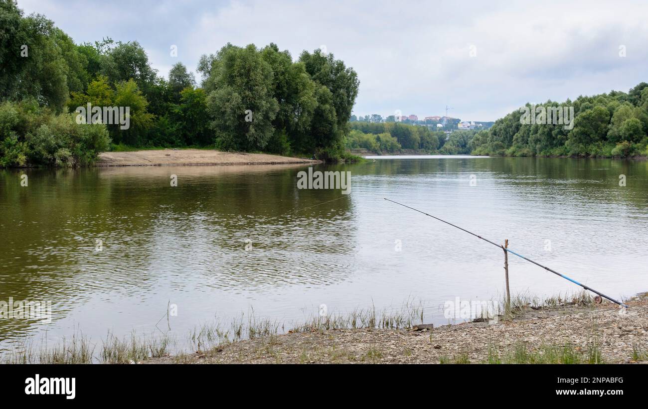 Des cannes à pêche se trouvent sur les rives de la rivière en attendant que le poisson mord en été en Russie. Banque D'Images