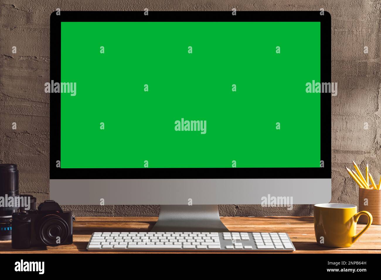 Ordinateur à écran vert Chroma Key avec équipement de photographie sur table. Plan d'examen de l'espace intérieur avec effet de lumière de fenêtre. Banque D'Images