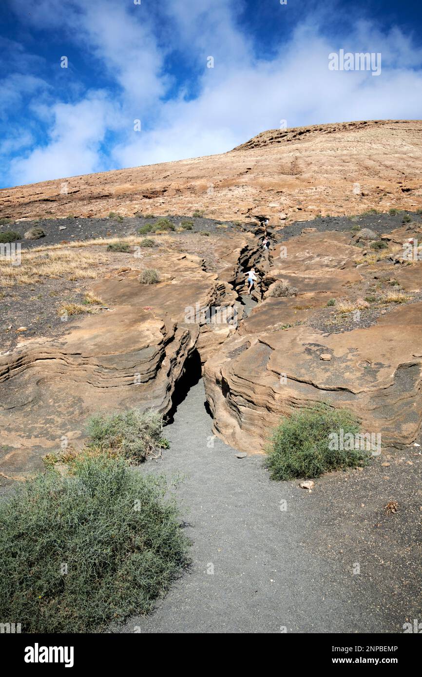 Touristes marchant vers le haut Ladera Del volcan Las Grietas Lanzarote, îles Canaries, Espagne formations rocheuses volcaniques causées par l'érosion avec vue sur montana bla Banque D'Images